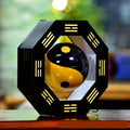 Decorative item with a black and yellow ball inside an octagonal frame on a blurred background
