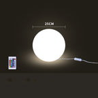 White spherical light with remote control and cable on a dark background