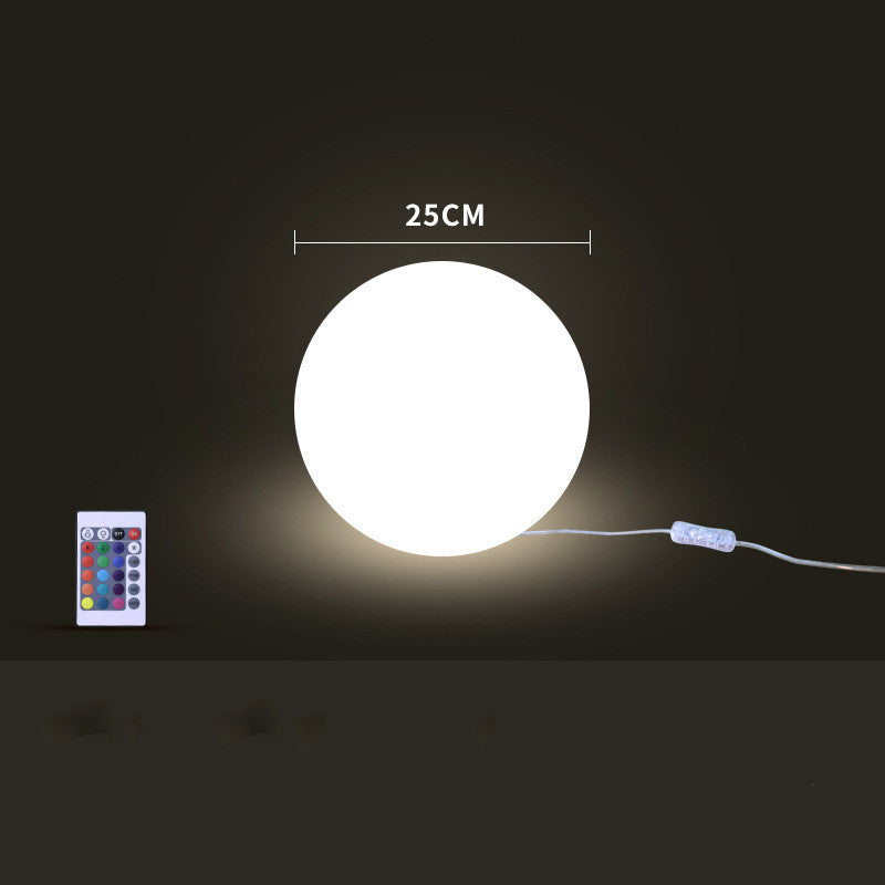 White spherical light with remote control and cable on a dark background