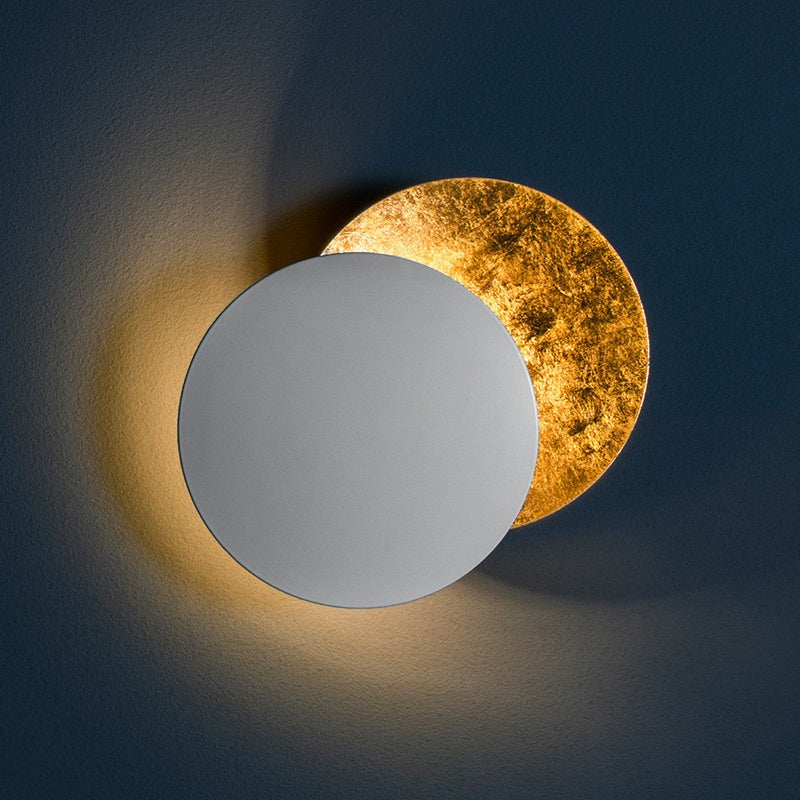 Two circular wall lights, one gold and one silver, on a dark background.