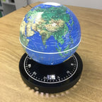 Globe on a wooden table with a visible brand logo.