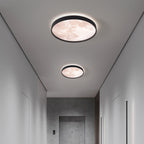 Two round ceiling lights in a modern hallway with neutral walls and a door.