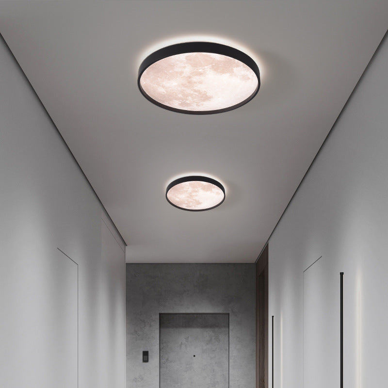 Two round ceiling lights in a modern hallway with neutral walls and a door.