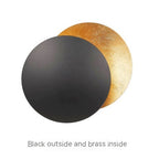 Two round objects, one black and one brass, on a white background.