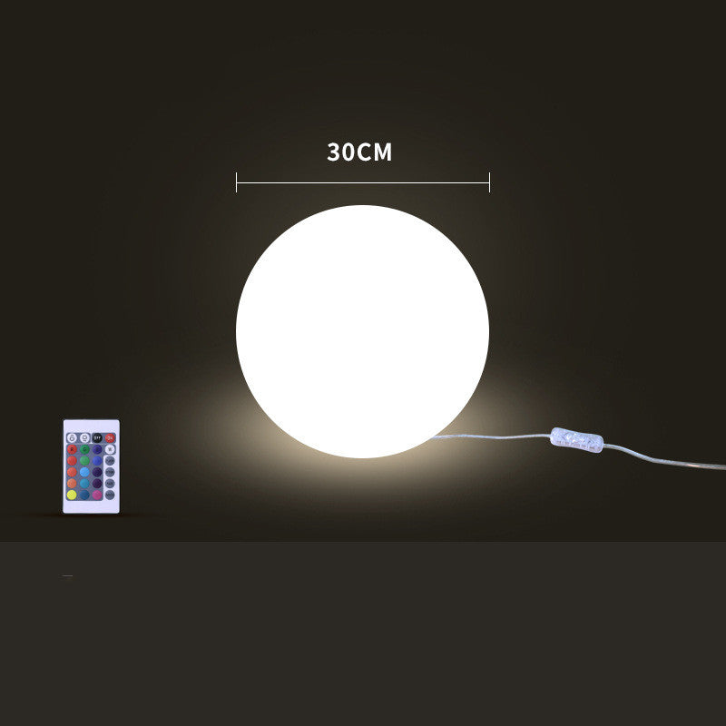 Round illuminated object with a remote control on a dark background