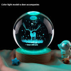 Decorative crystal ball with deer design and color-changing light on a wooden base.