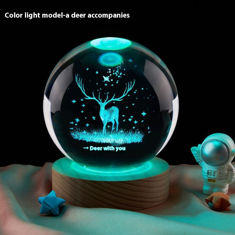 Decorative crystal ball with deer design and color-changing light on a wooden base.