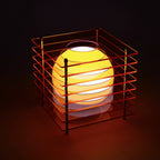 Yellow spherical lamp inside a red metal cage on a dark background