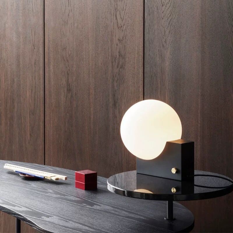 Modern table lamp on a dark wooden surface with a wooden panel background