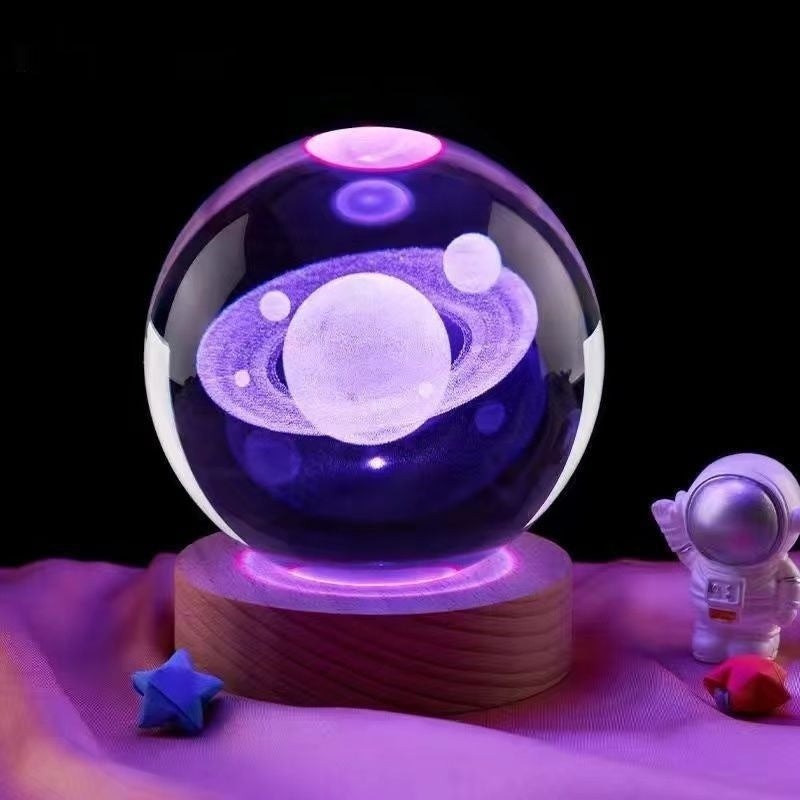 Crystal ball with planetary design on a wooden base, surrounded by small decorative items.