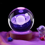 Crystal ball with planetary design on a wooden base, surrounded by small decorative items.