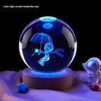 Crystal ball with blue light projection of an umbrella man figure on a wooden base.