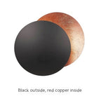 Two round objects, one black and one red copper, on a white background.