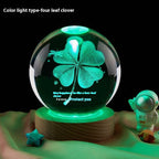 Glowing crystal ball with four-leaf clover design on a wooden base, surrounded by toys.